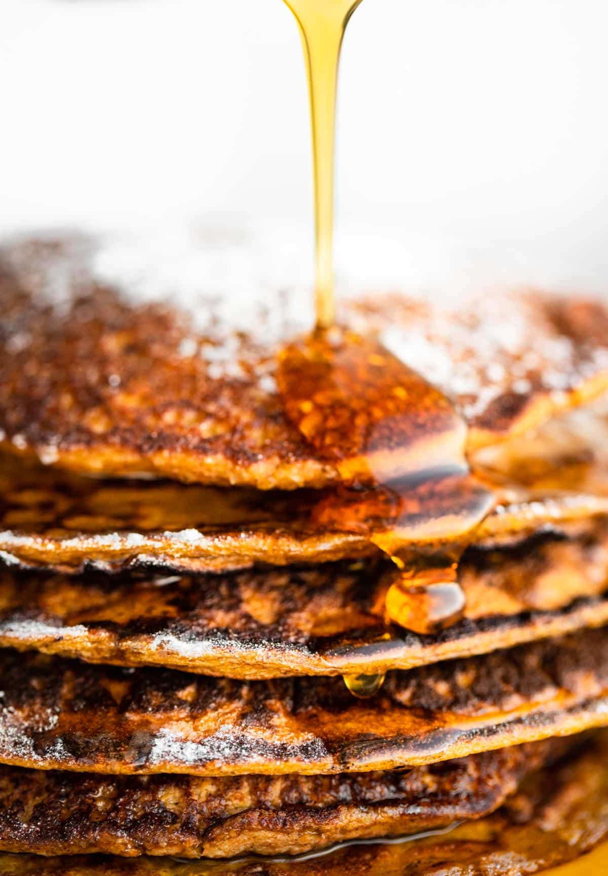 Close up of syrup being poured onto a stack of Gluten-Free Carrot Cake Pancakes.