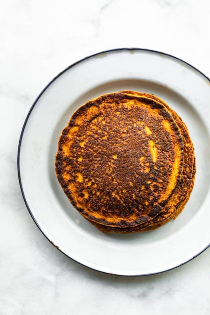 A stack of Gluten-Free Carrot Cake Pancakes on a plate.