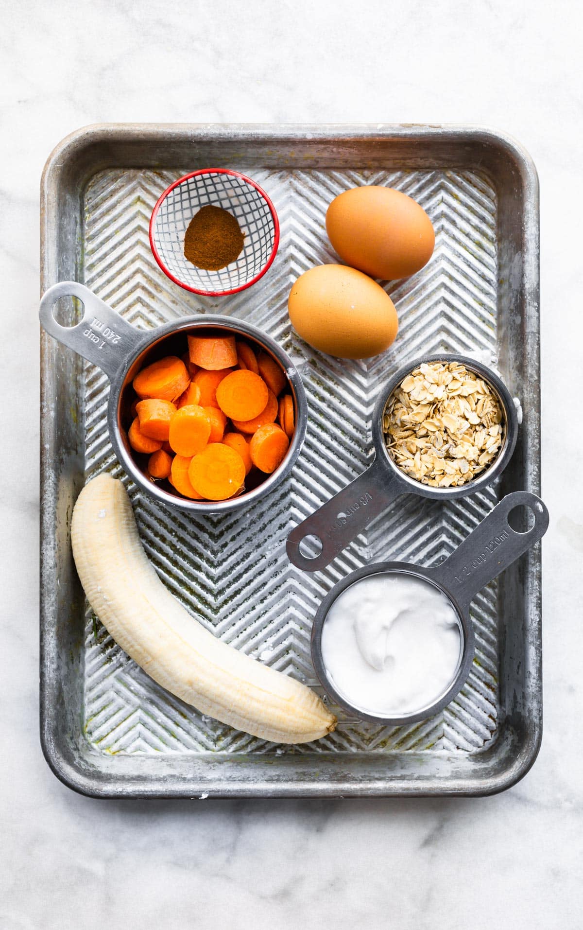 Assorted Gluten-Free Carrot Cake Pancakes ingredients - eggs, carrots, banana, oats, yogurt, and cinnamon.