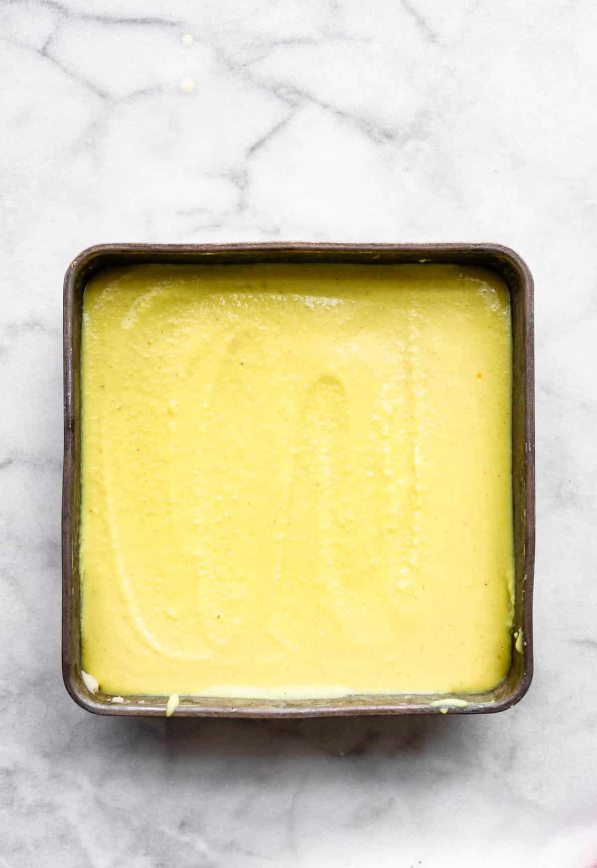 unbaked lemon cheesecake bars in a square baking pan
