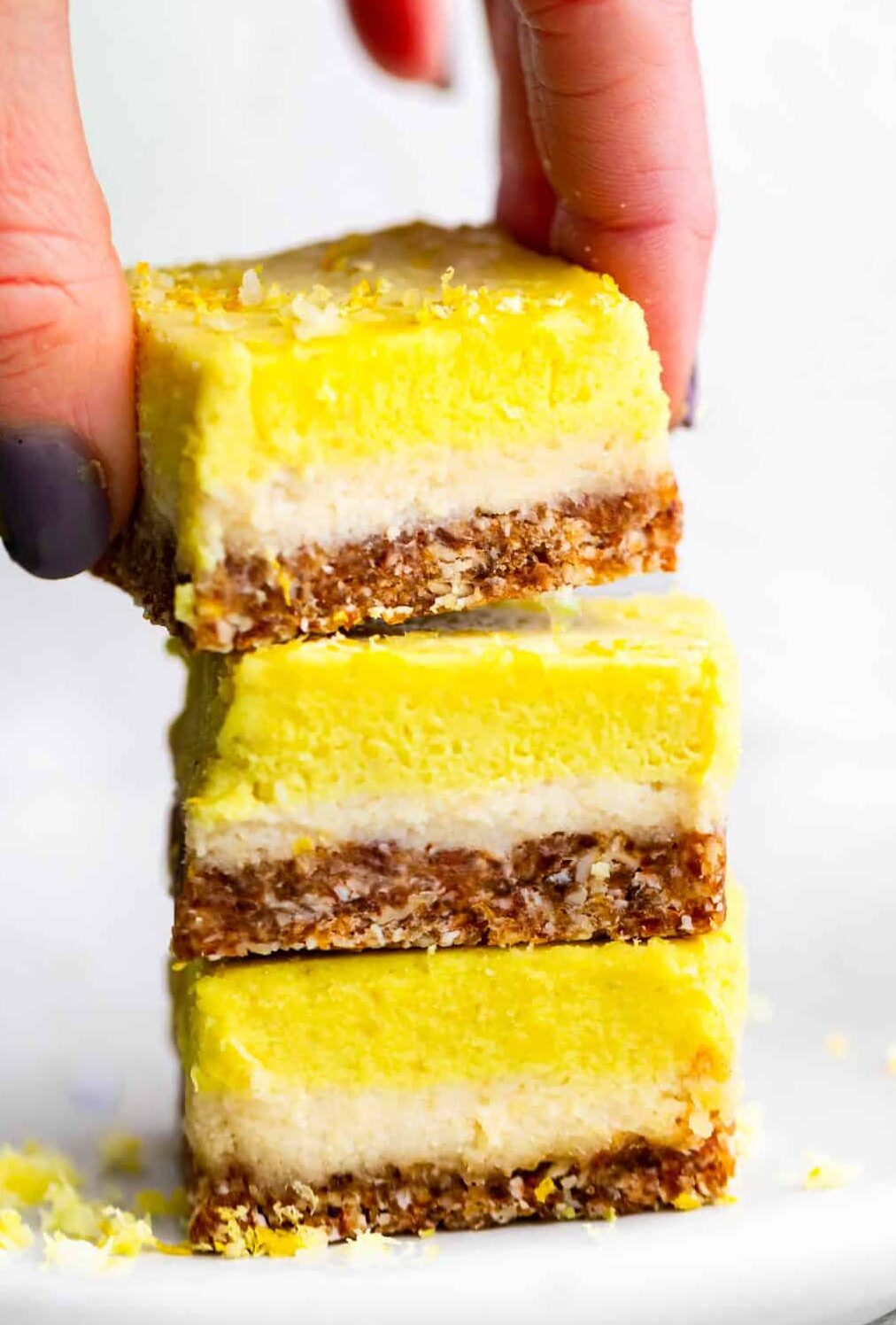 3 No Bake Lemon Cheesecake Bar pieces being stacked on top of one another.