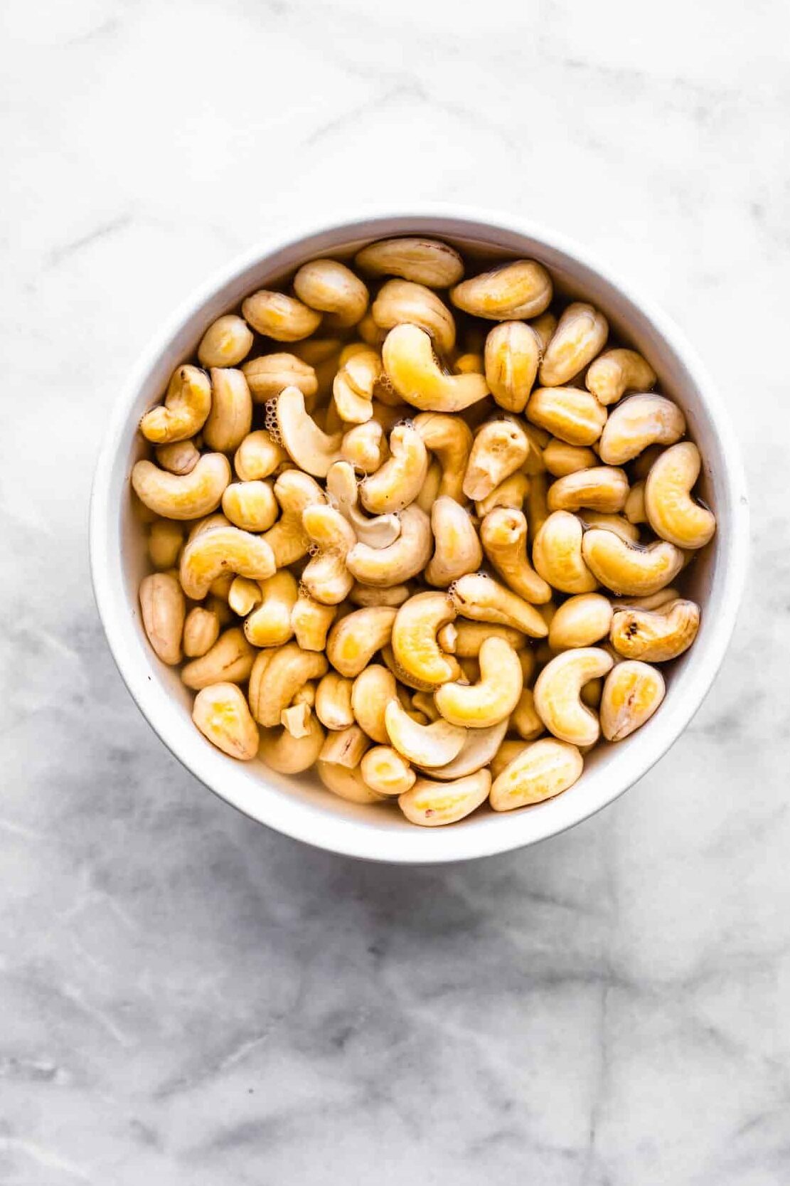 a bowl of cashews soaking in water