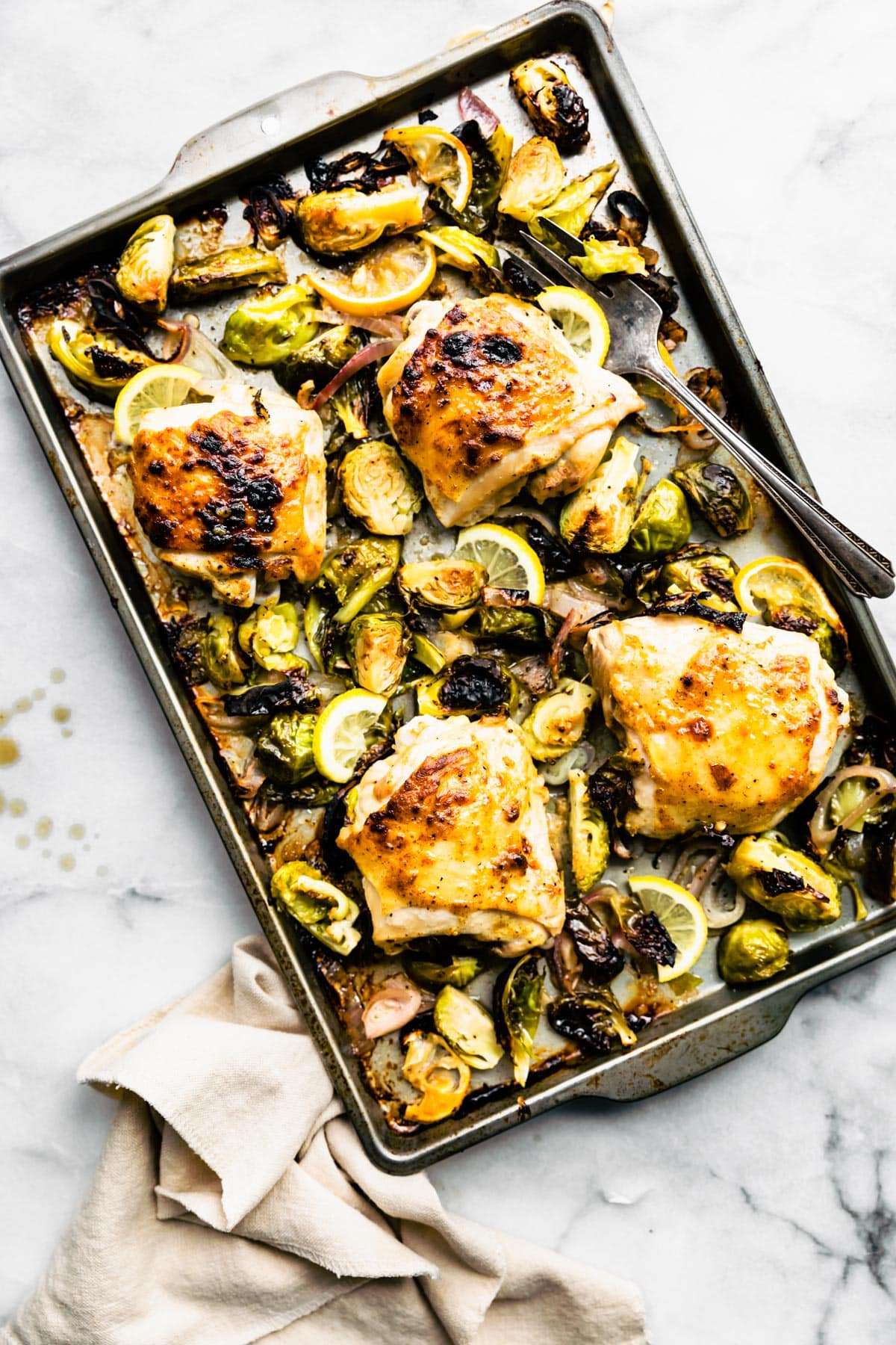 Cooked Honey Mustard Chicken Thighs with Brussels Sprouts on a baking sheet and ready to be served