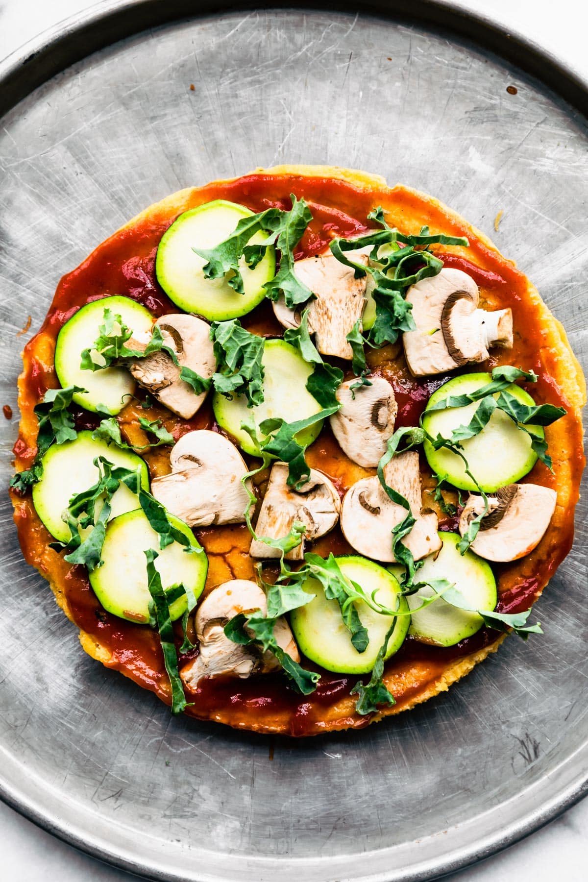 Socca Pizza topped with mushrooms, zucchini and sauce.