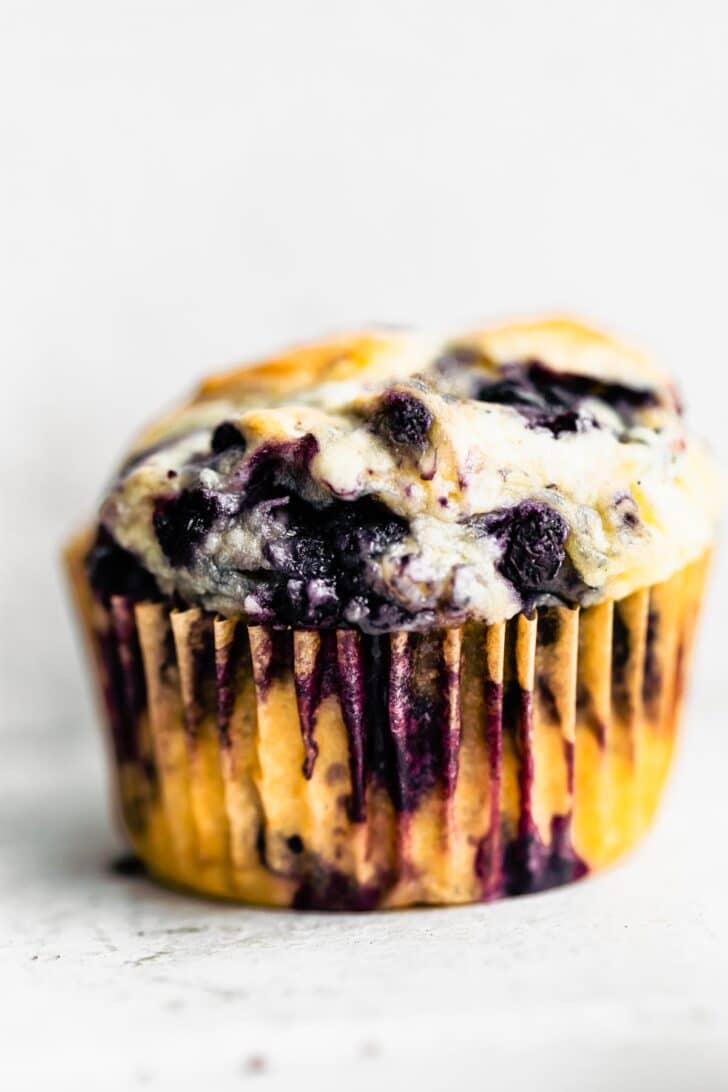 Side view of a gluten free blueberry muffin in a muffin liner.