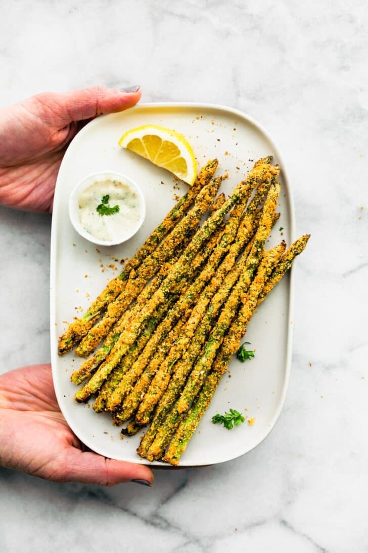 Air fryer asparagus fries on a white plate with a side of aioli.