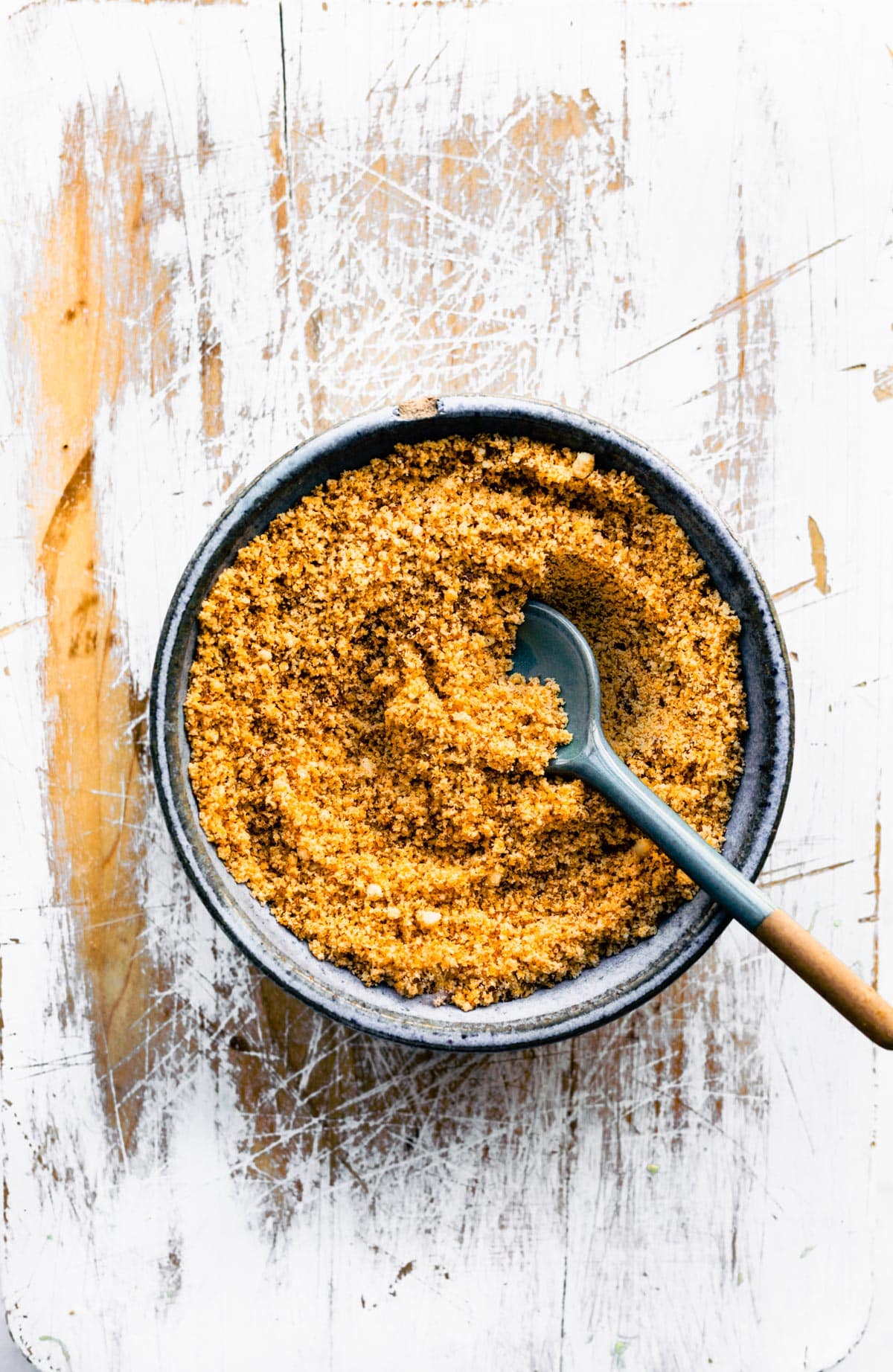 A bowl of homemade gluten-free panko breadcrumbs with a spoon sticking out.