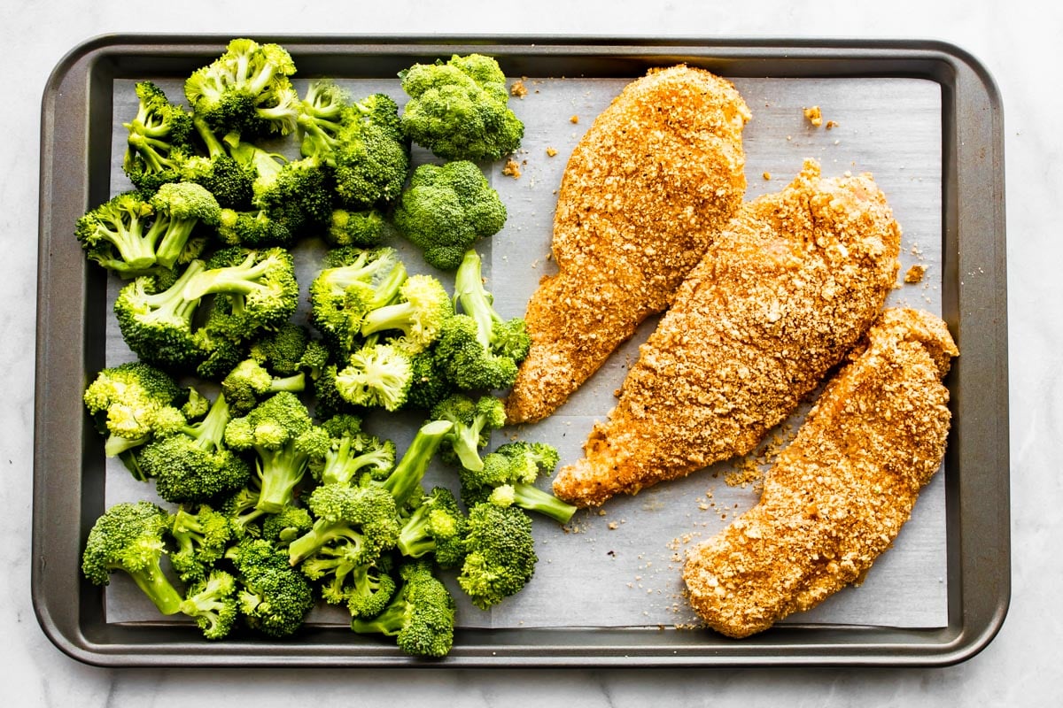 Gluten-Free Panko Chicken breasts on a sheet pan with broccoli.