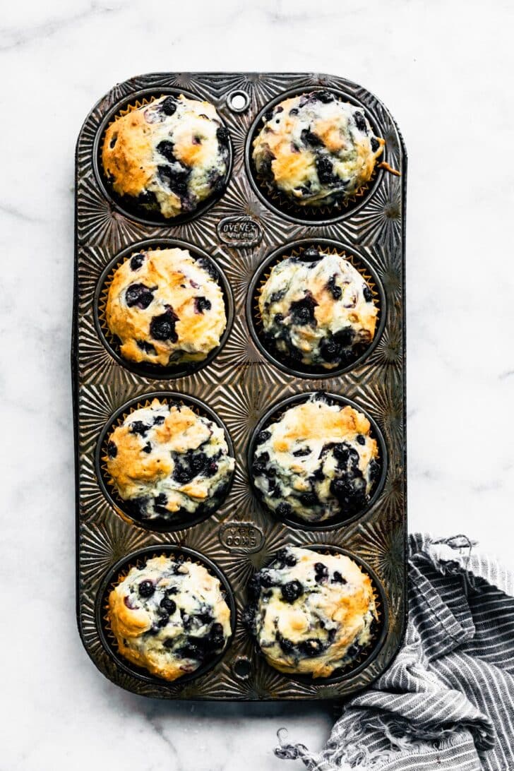 A muffin tin full of 8 baked gluten free blueberry muffins.