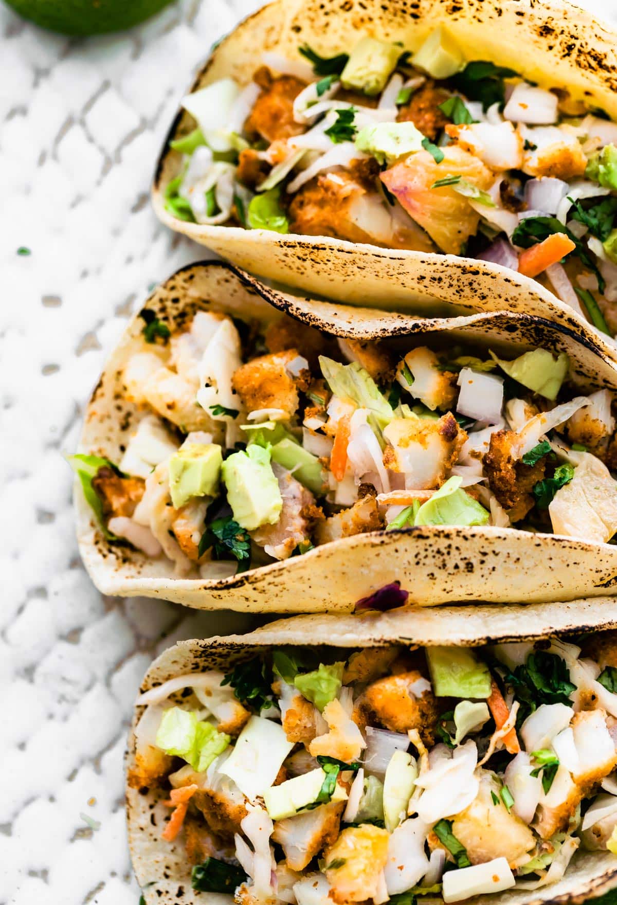 Close-up image of three gluten-free air fryer fish tacos topped with pineapple slaw.