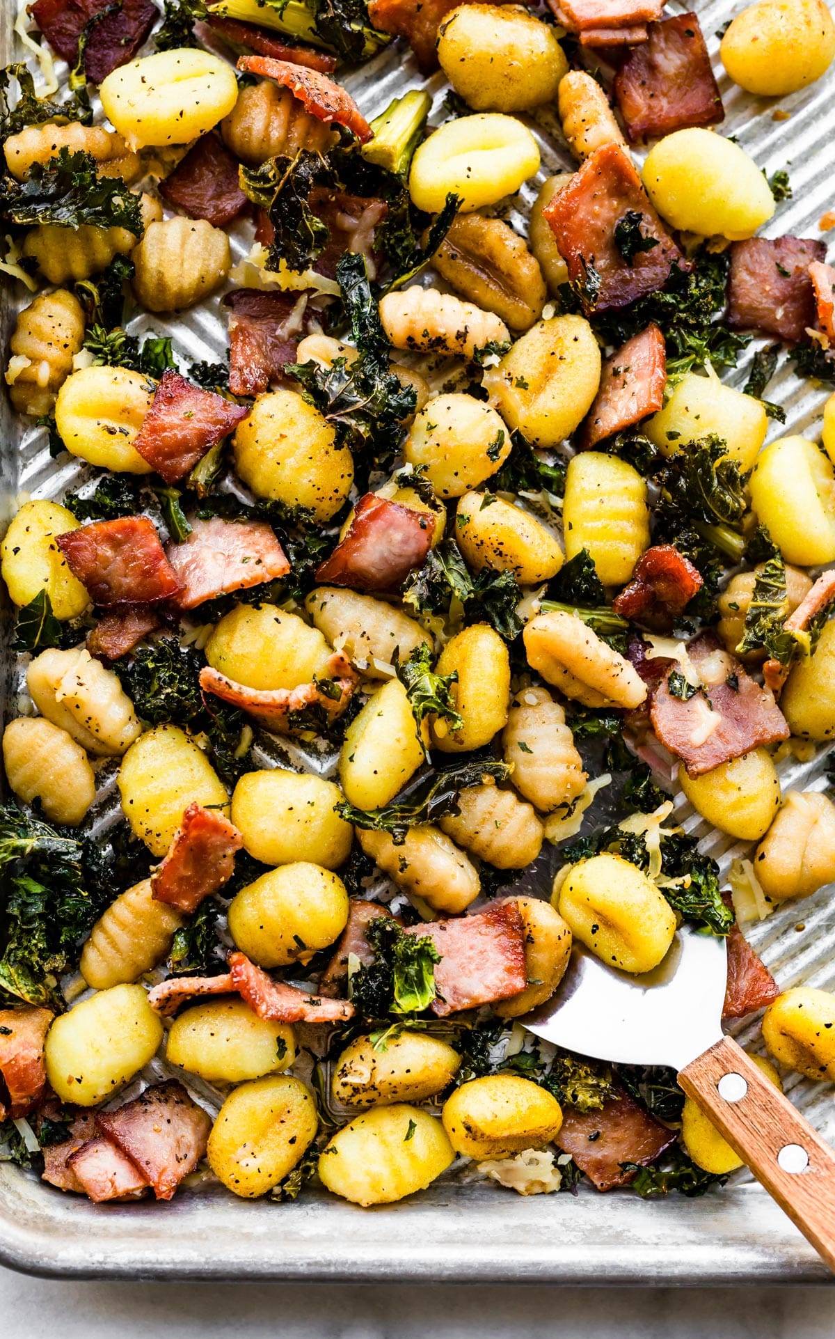 A sheet pan with gluten-free bake gnocchi, bacon, and kale.