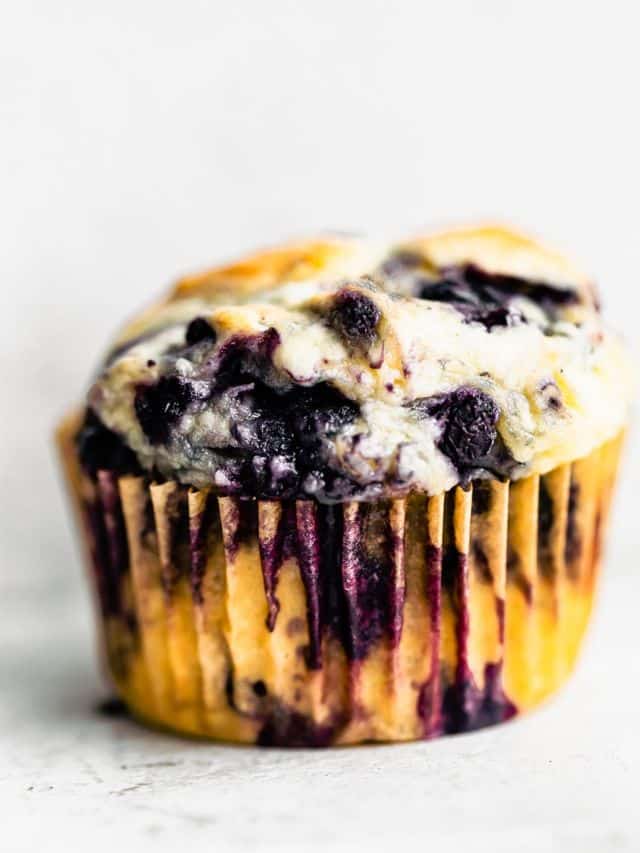 Side view gluten free blueberry muffin in paper liner
