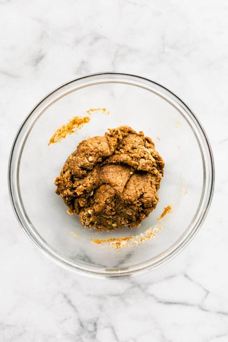 Overhead image of a glass bowl with a ball of gluten free cookie bar dough.