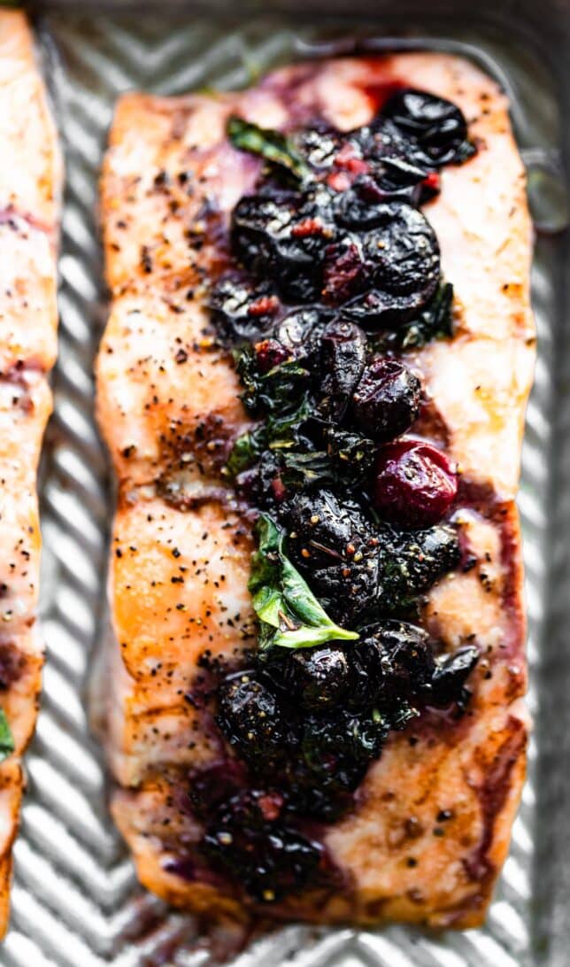 Close up image of a baked salmon filet topped with a blueberry compote.