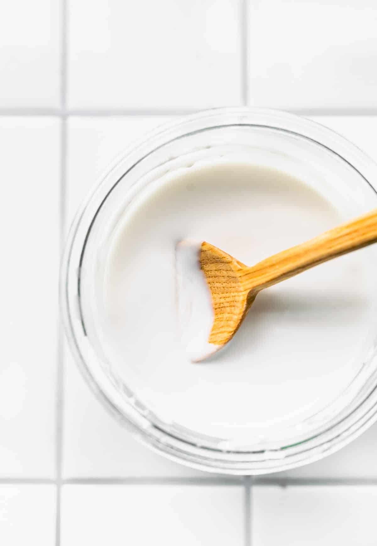 Overhead image of a wooden spoon stirring coconut milk yogurt.