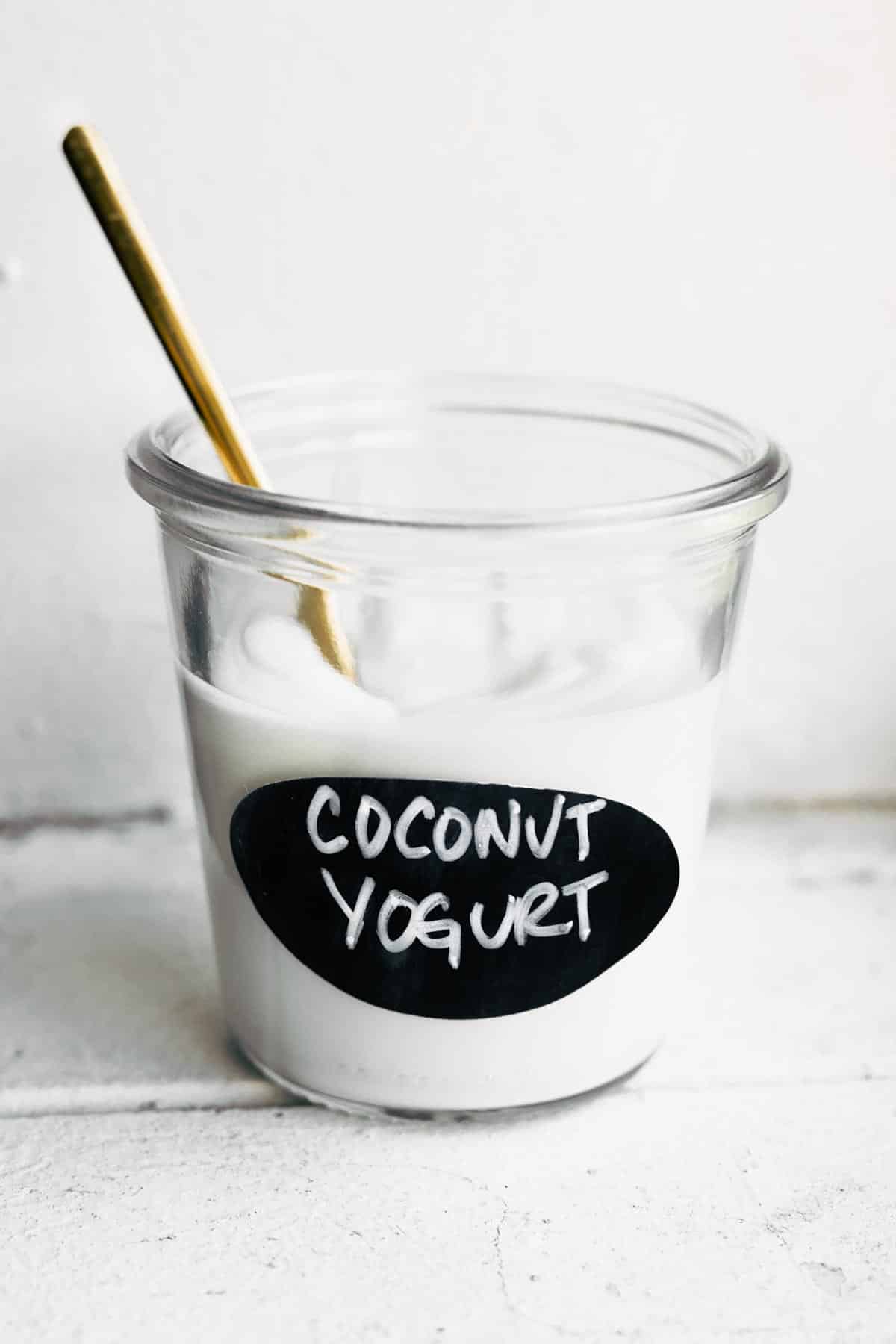A glass jar labeled "coconut yogurt" full of homemade coconut milk yogurt.