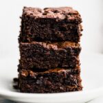 Three gluten free brownies stacked on top of each other on a plate.