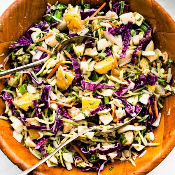 Overhead image of a bowl of easy pineapple coleslaw with two serving spoons sticking out.