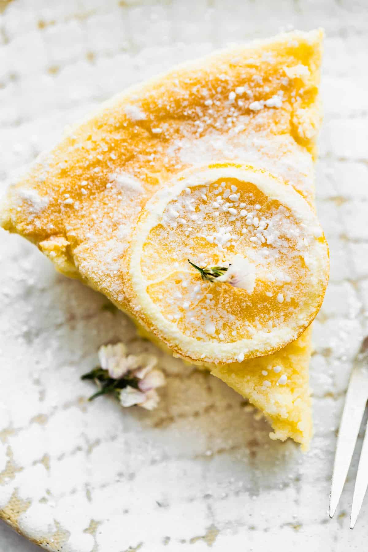 Overhead image of a slice of gluten free lemon pudding cake dusted with powdered sugar.