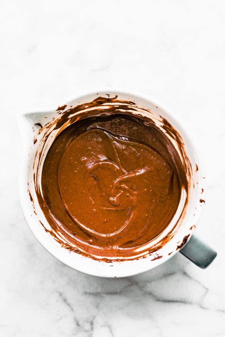Overhead image of a measuring cup full of gluten free chocolate cake batter.