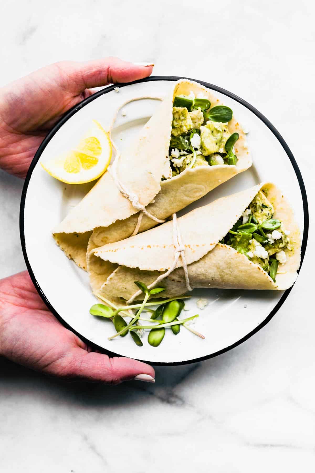 A plate with two green goddess chicken salad wraps.