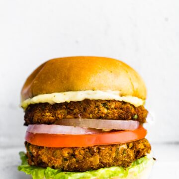 One dairy free cauliflower chickpea burger on a gluten free bun with toppings.