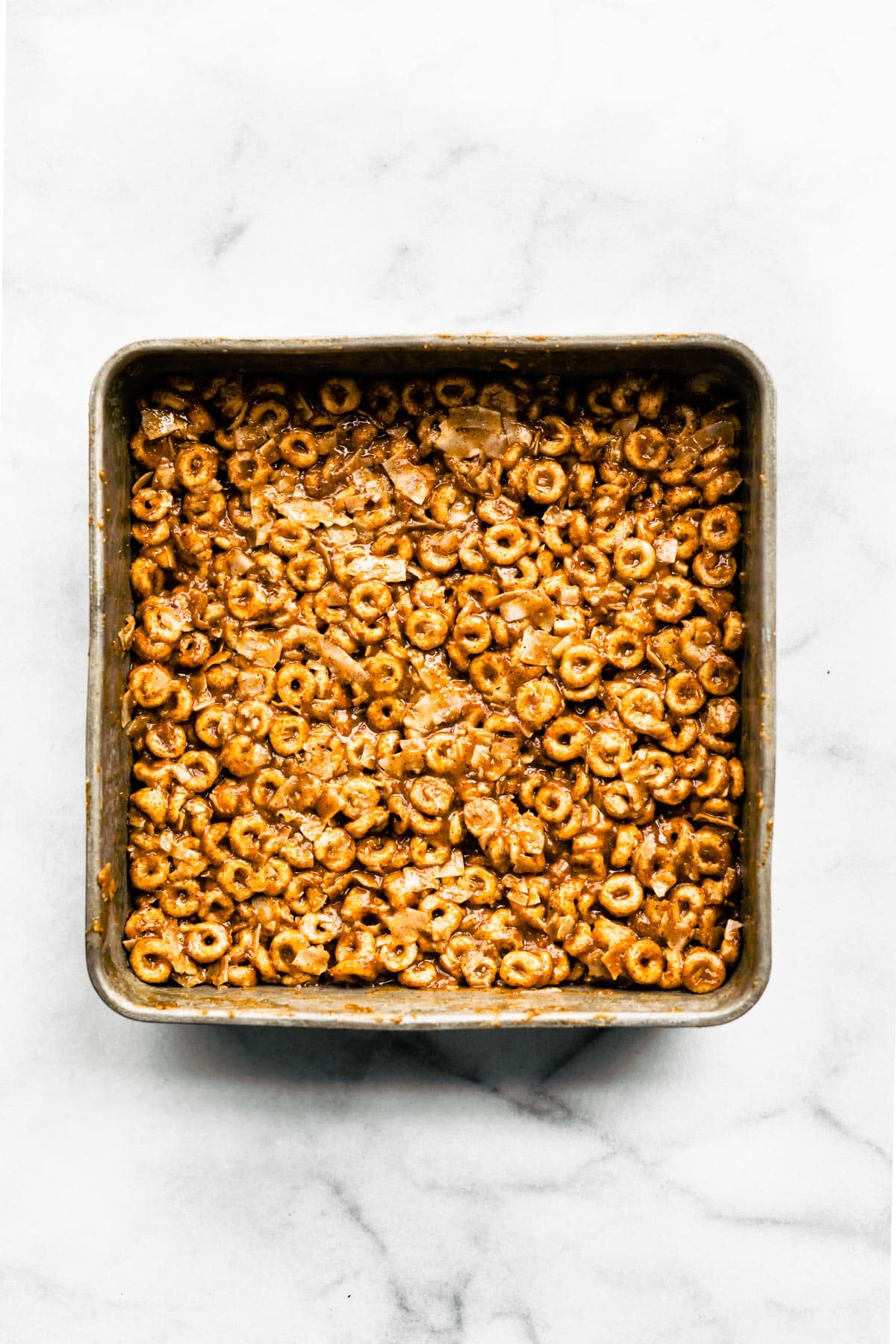 A pan of no bake gluten free cereal bars on a white marble countertop.