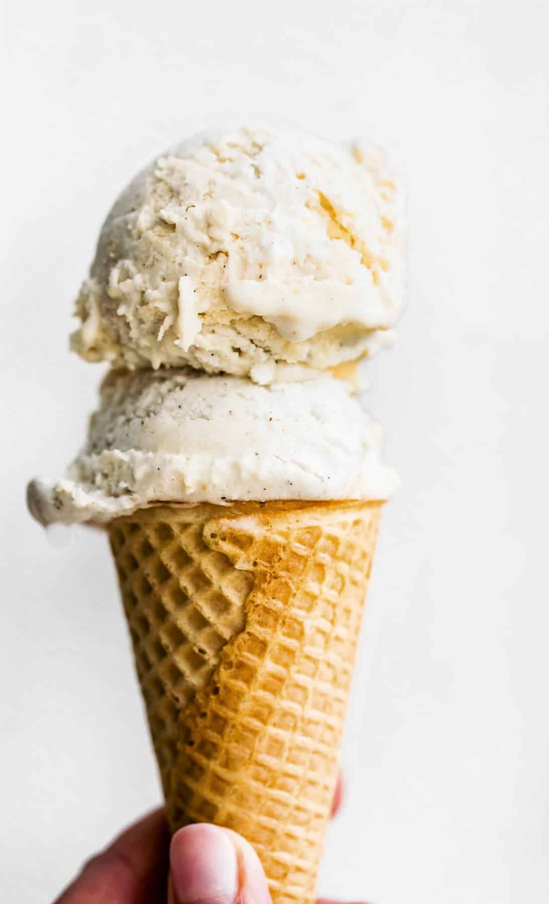 Vegan ice cream on top of a sugar cone against a white background.