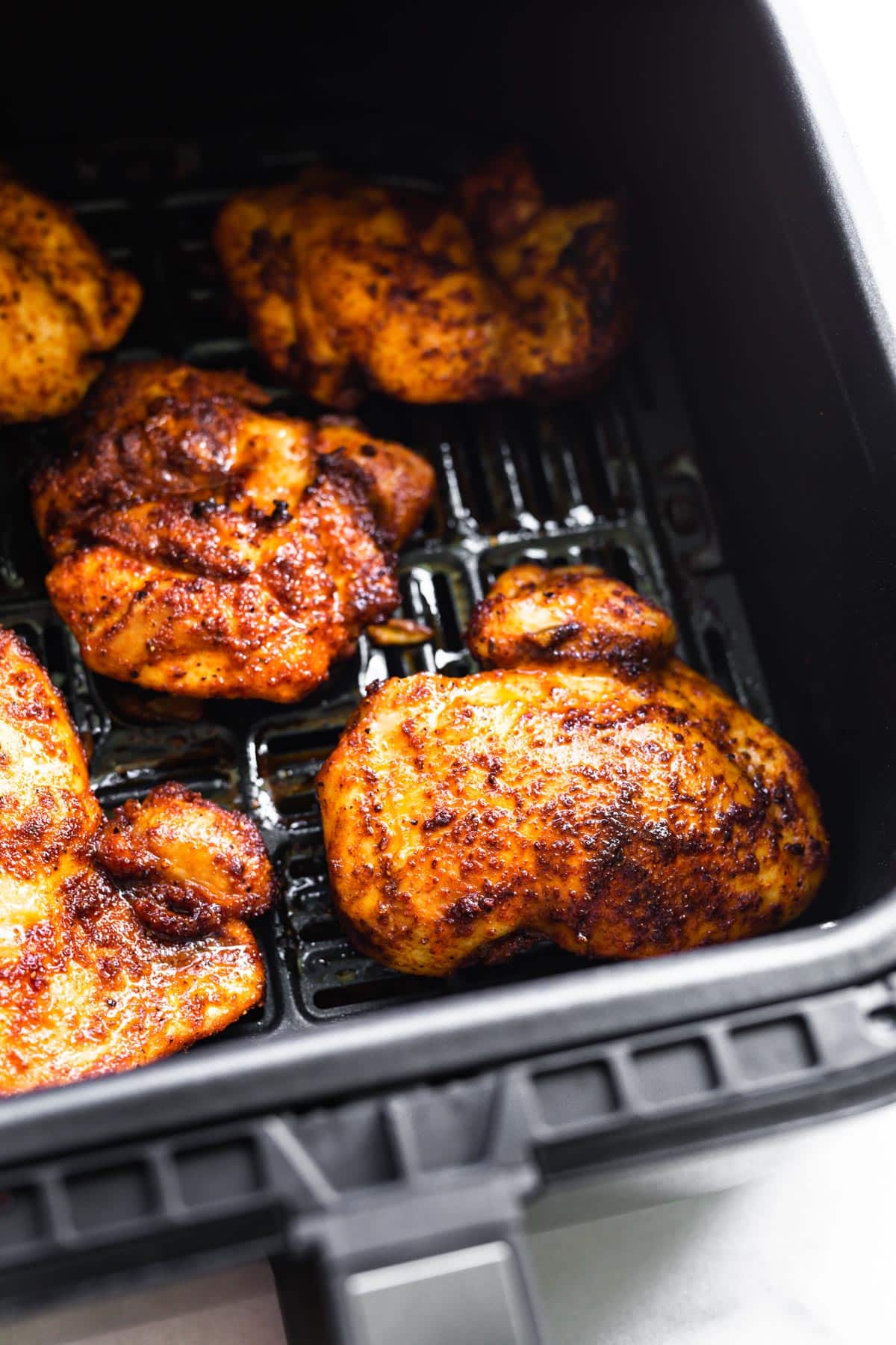 Baked paprika chicken thighs in an air fryer basket.