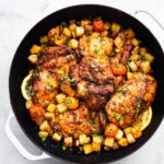 Overhead photo of gluten free paprika chicken thighs surrounded by diced veggies in a pan.