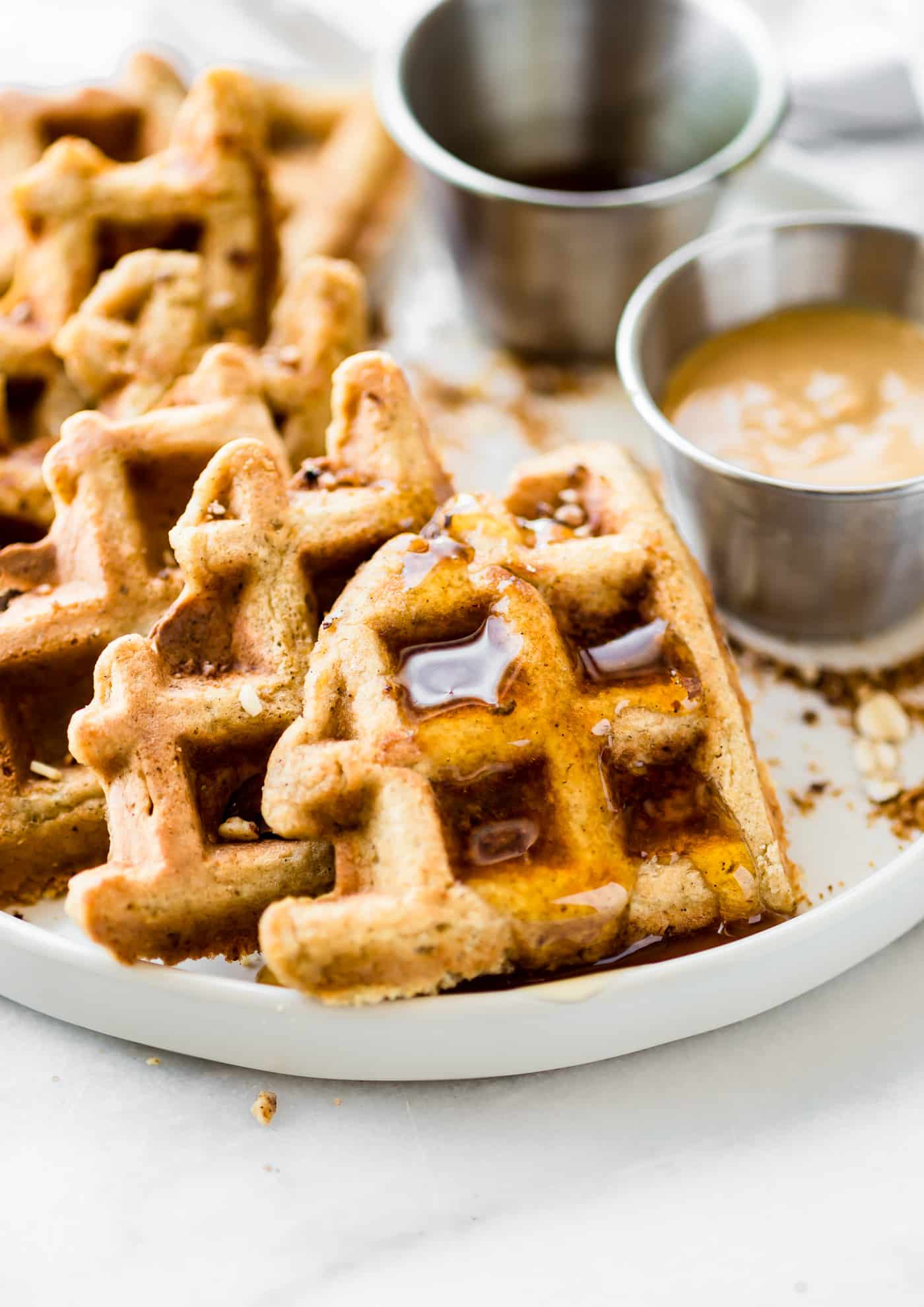 Wedges of peanut butter waffles on a plate drizzled with maple syrup.