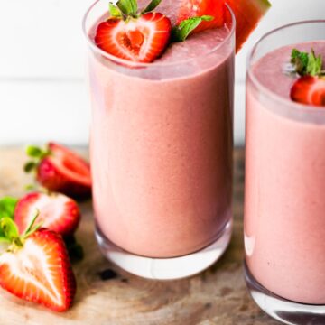 Two glasses with dairy free watermelon smoothie topped with halved strawberries.