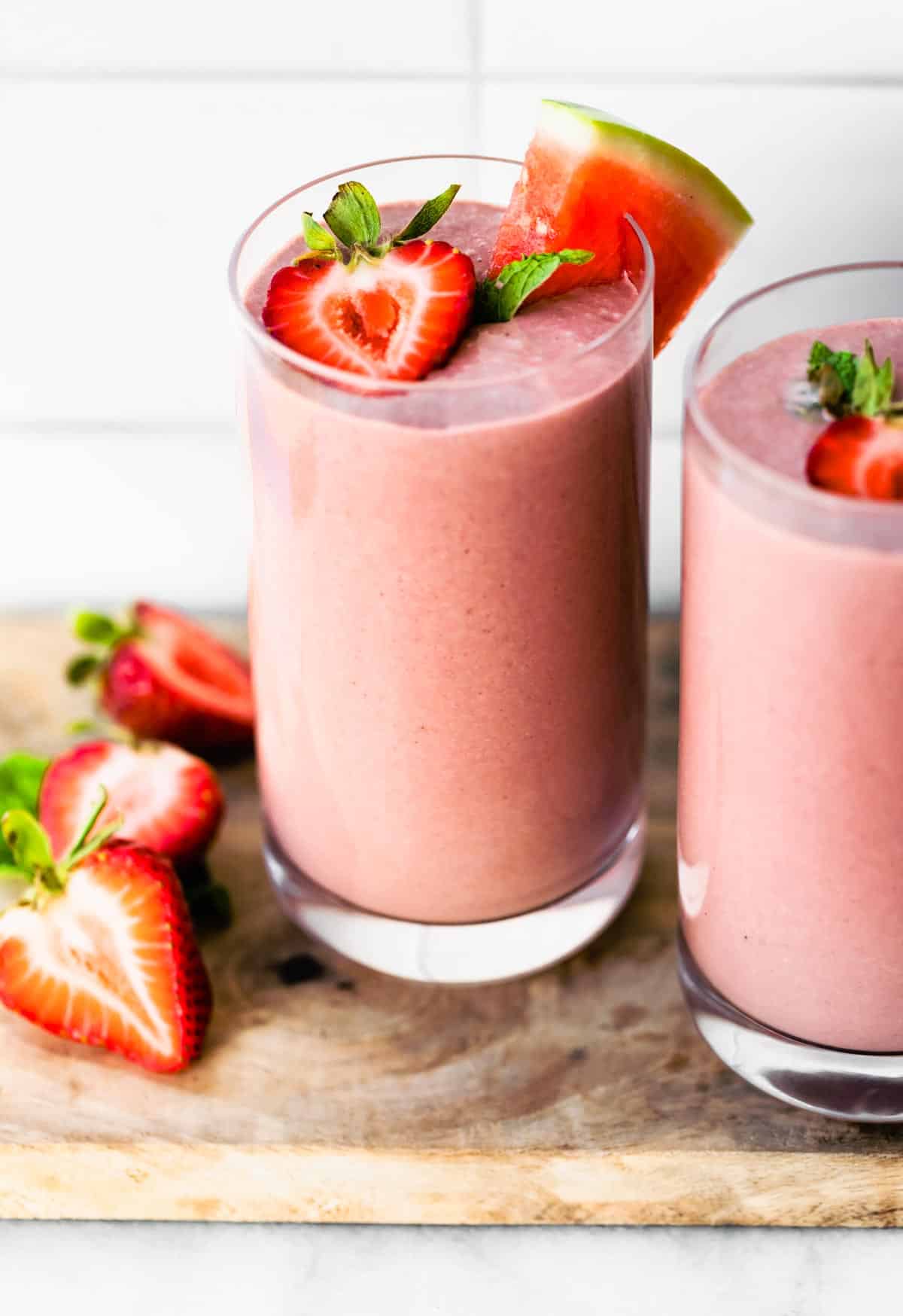 Two glasses with dairy free watermelon smoothie topped with halved strawberries.