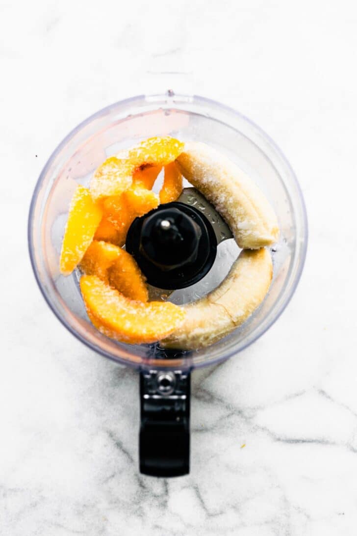 Whole frozen peaches and bananas in a food processor.