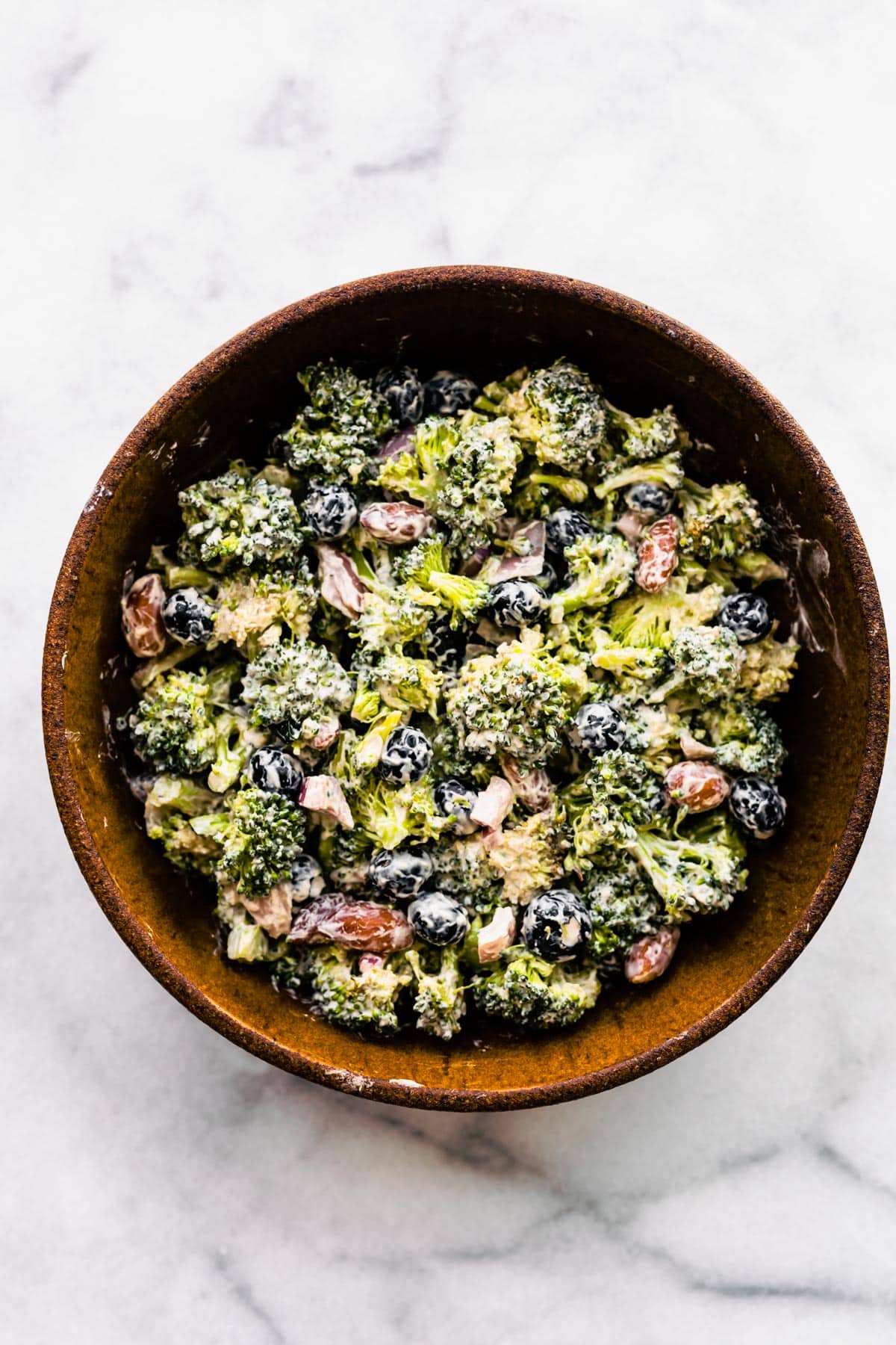 A large wooden bowl with a healthy broccoli salad.