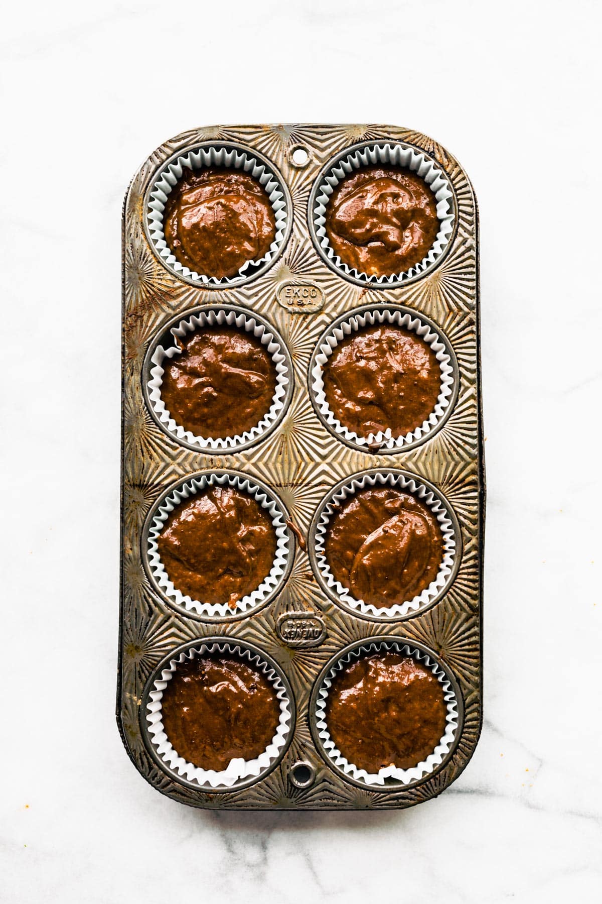 Gluten free chocolate banana muffins in an 8 count muffin tin.