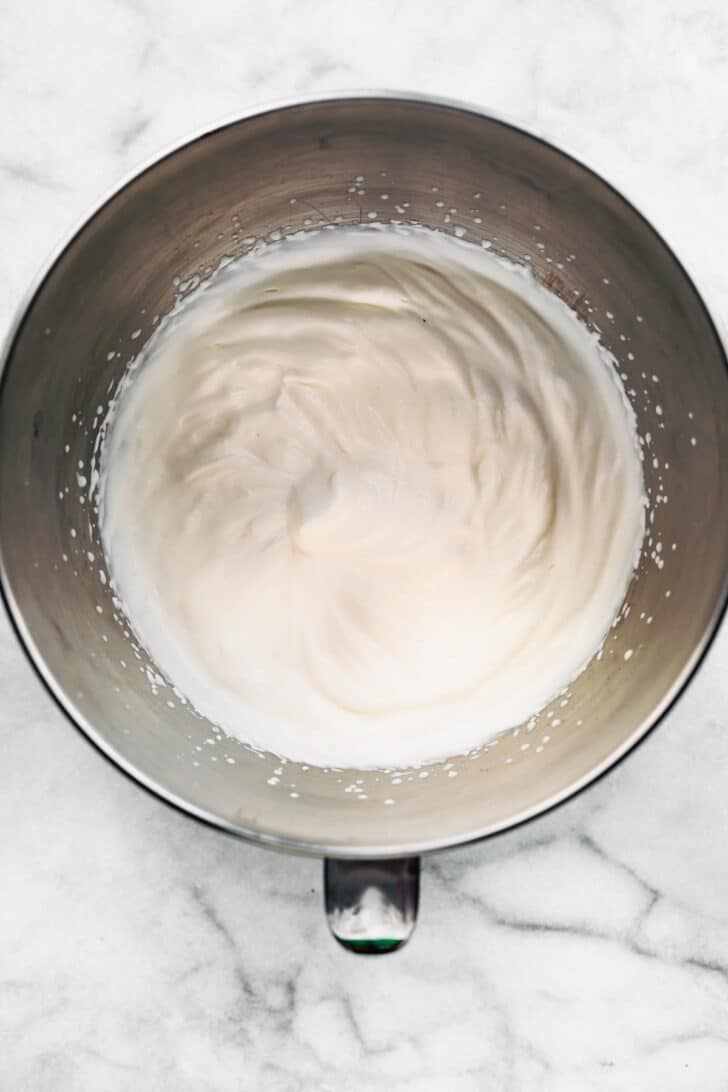 Overhead view of fluffy coconut milk in a metal mixing bowl.