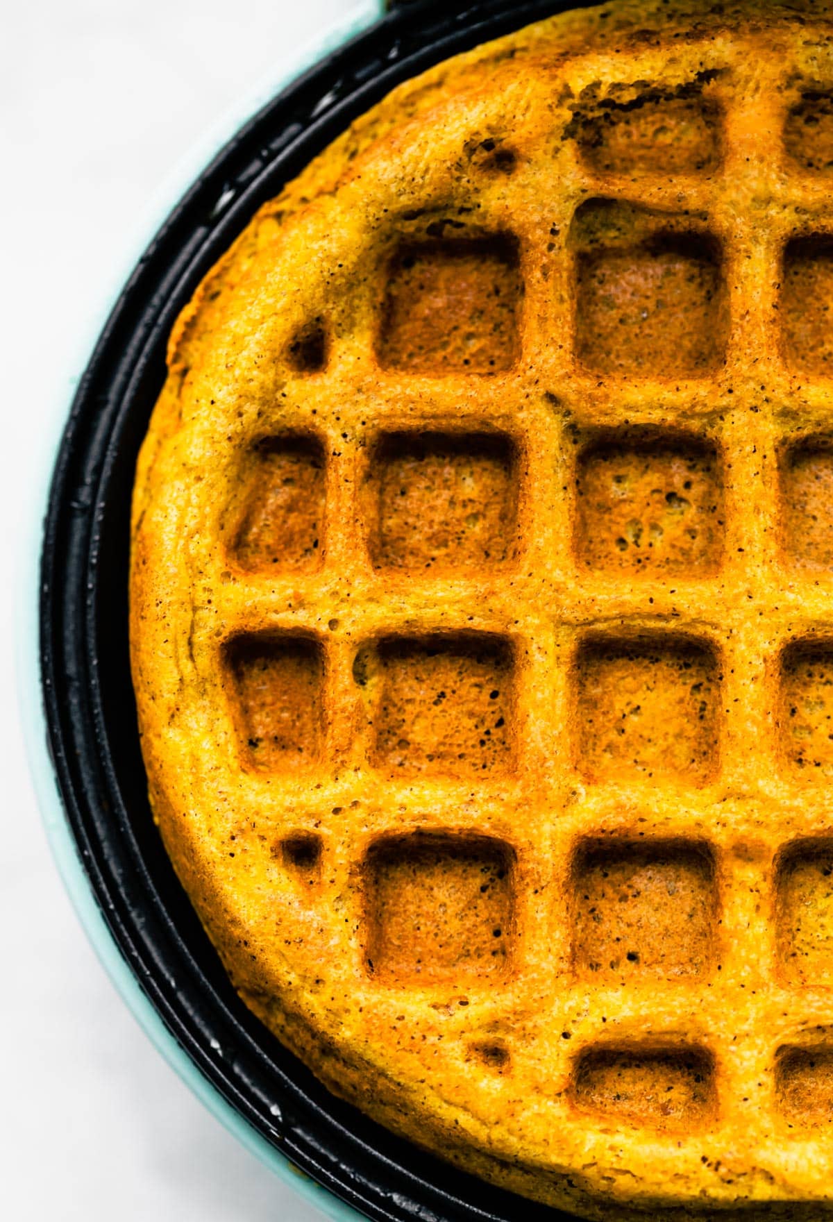 Up close overhead photo of a pumpkin waffle in a waffle maker.