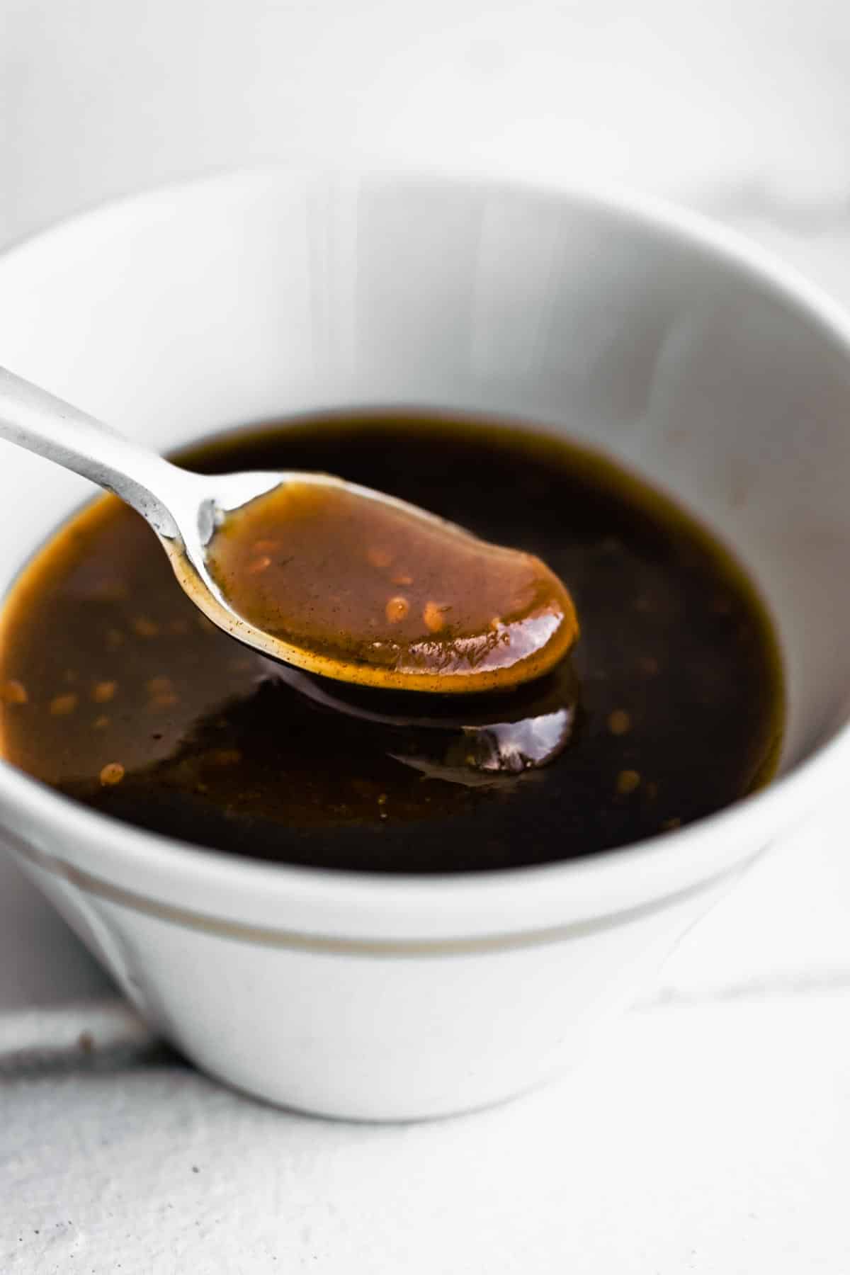 A spoonful of gluten free teriyaki sauce in a white bowl.