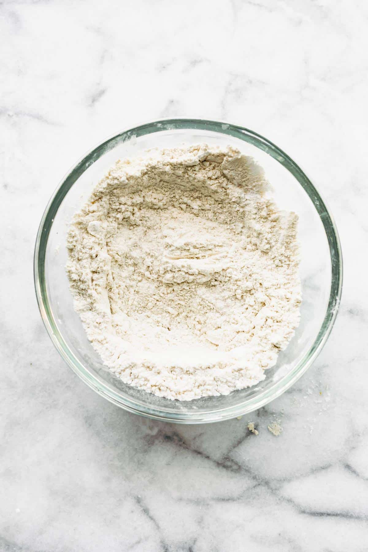 A clear glass bowl filled with a homemade gluten free flour blend.