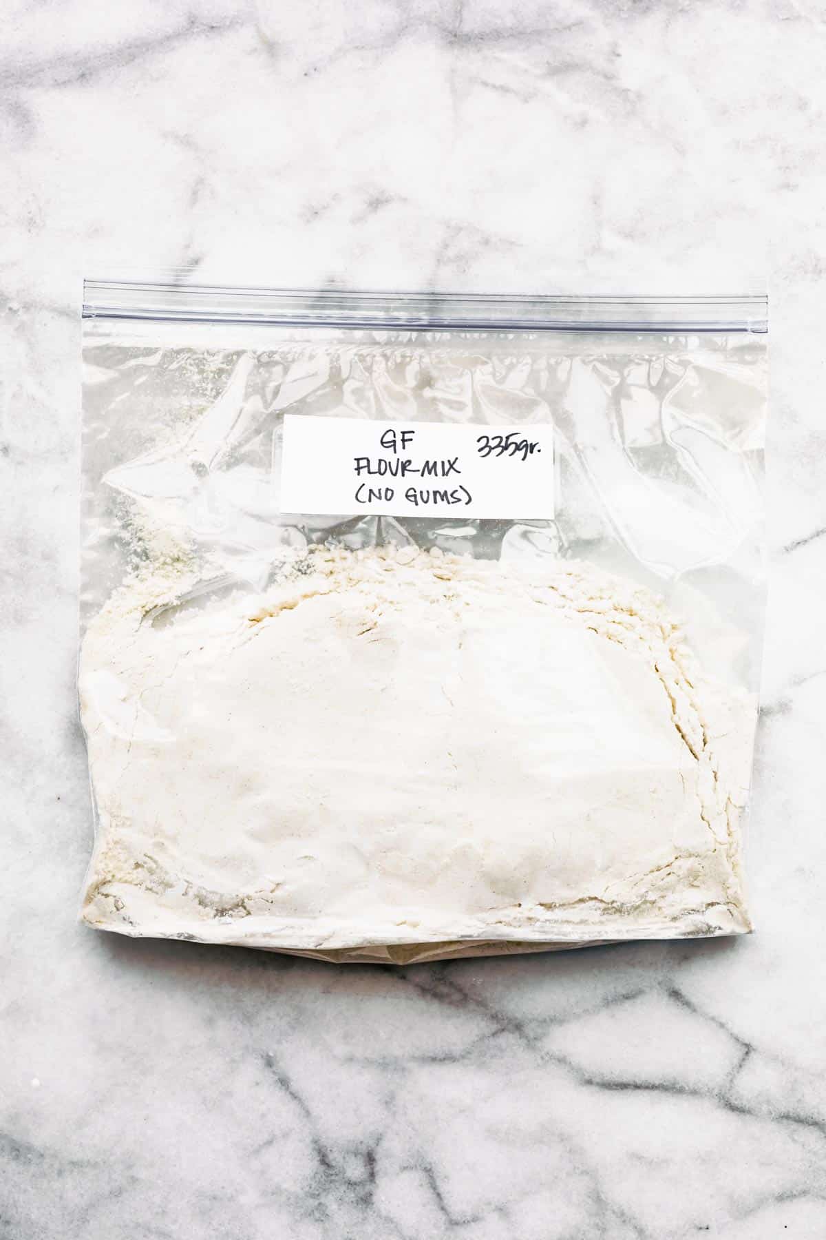 A ziploc bag with a homemade gluten free flour mix on a white marble countertop.
