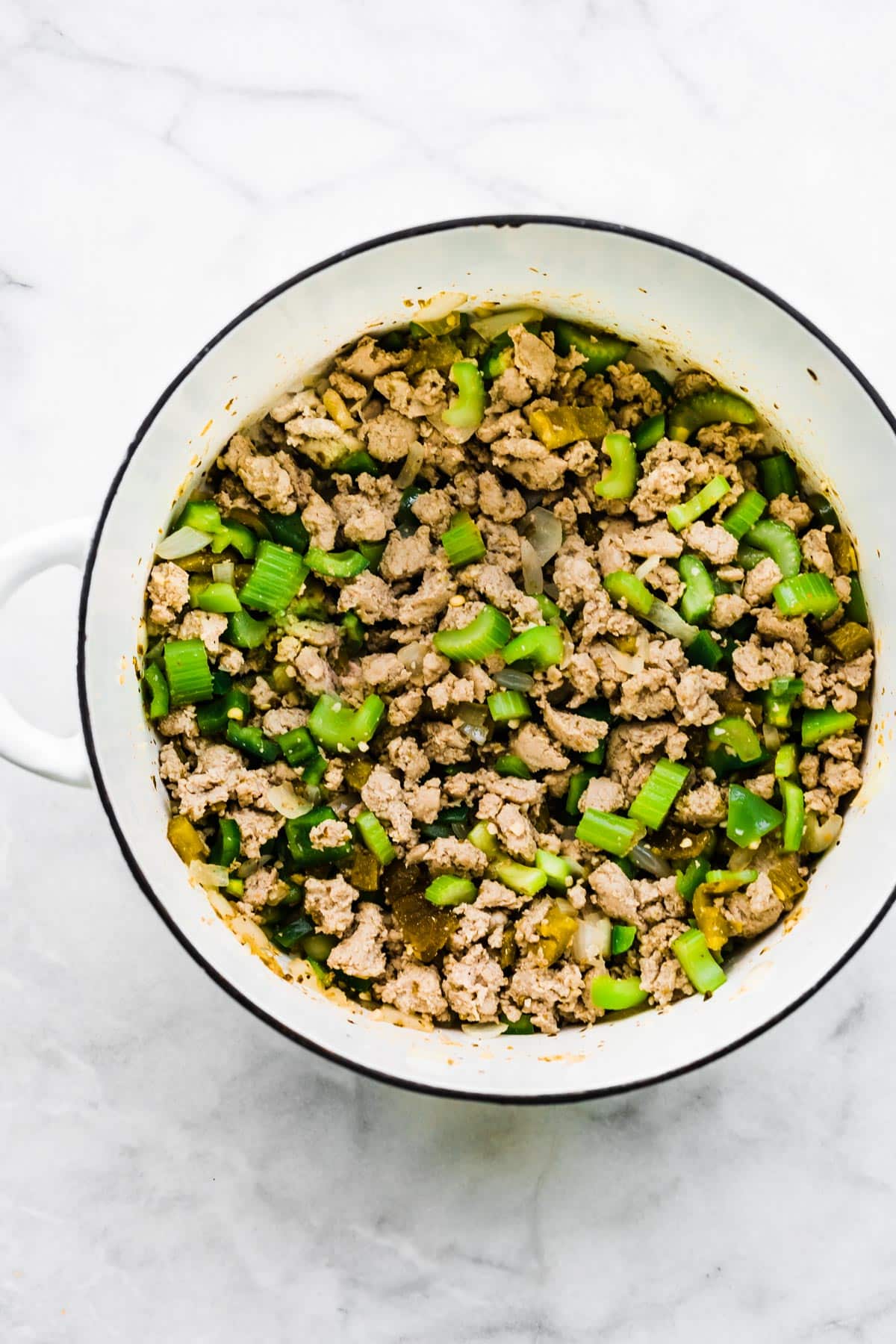 Browned ground turkey with diced celery in a large white soup pot.