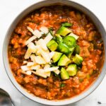 Overhead photo of no bean chili topped with shredded cheese, jalapenos and avocado.