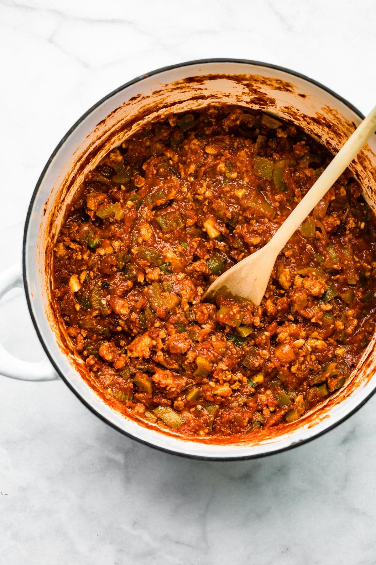 Overhead photo of a pot of no bean chili with a wooden spoon in it.