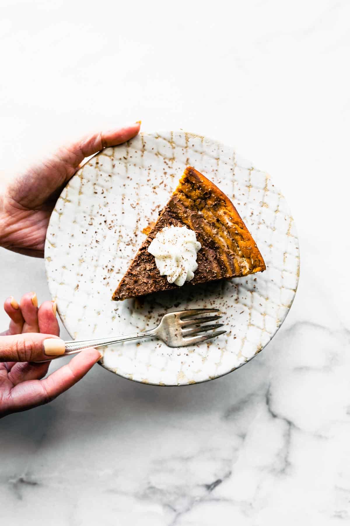 A woman holding a plate with a piece of crustless chocolate pumpkin pie.