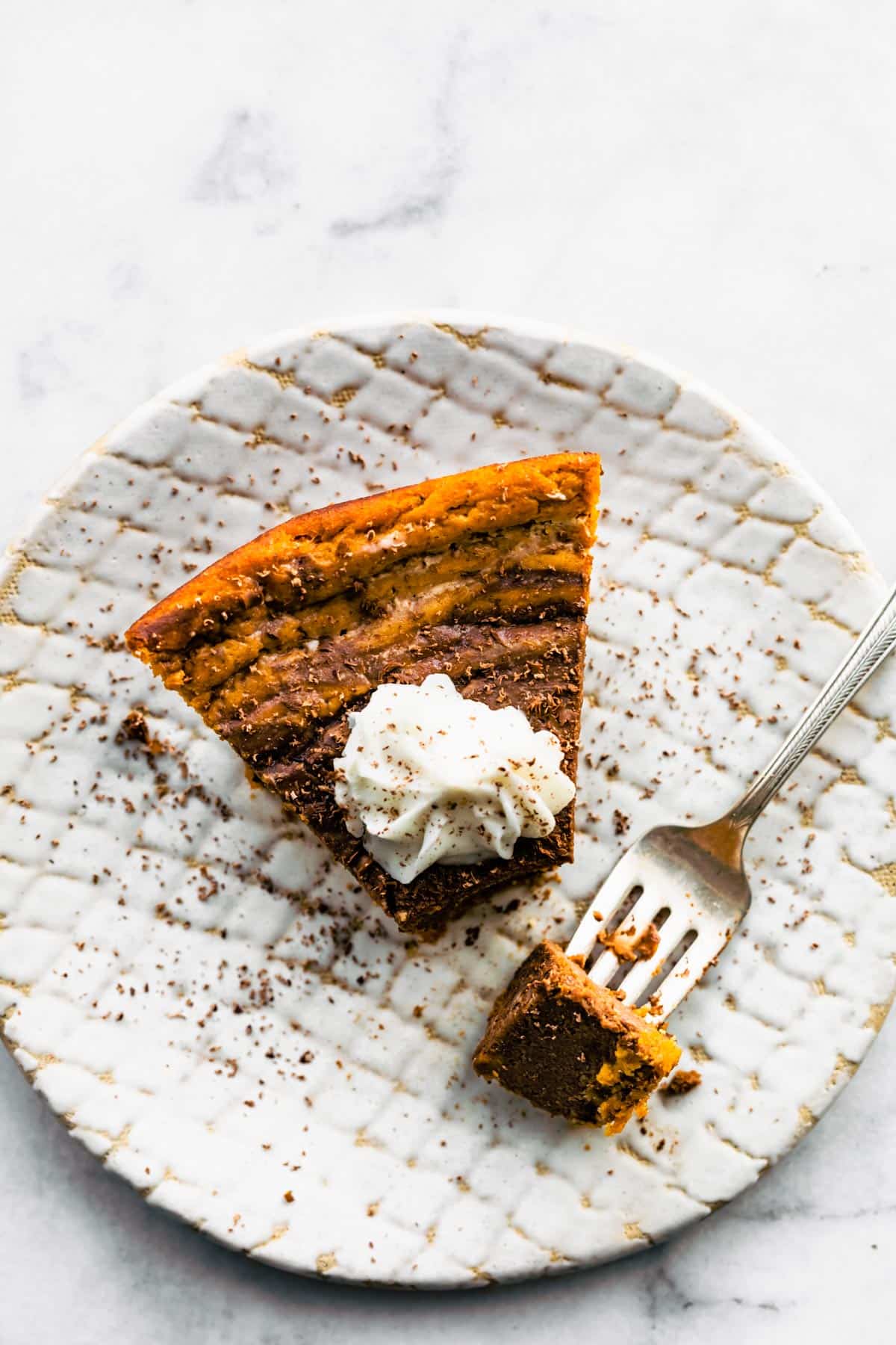 Overhead photo of a piece of bourbon chocolate pumpkin pie with a fork in it.