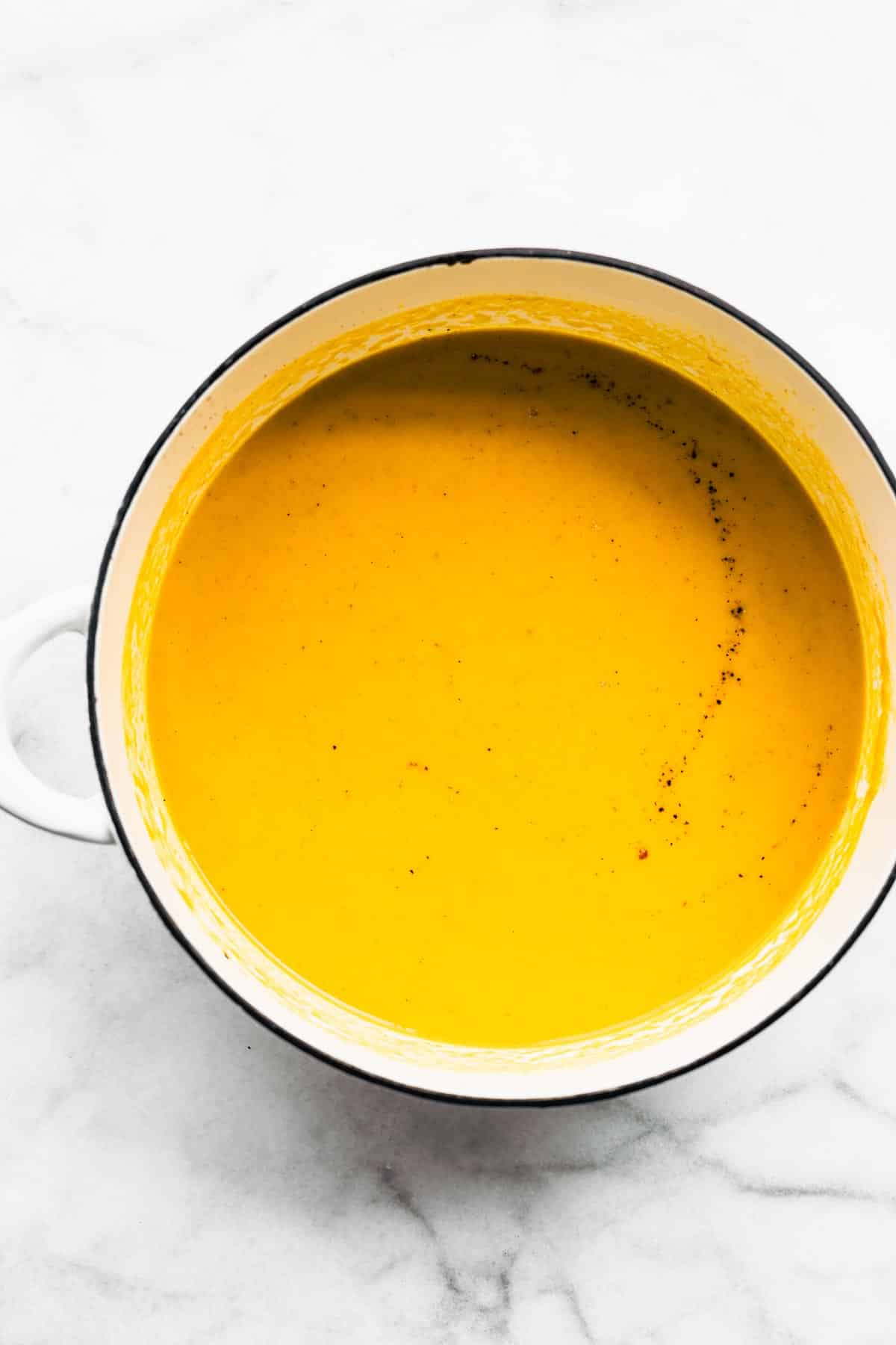 Overhead photo of a white soup pot filled with vegan butternut squash soup.