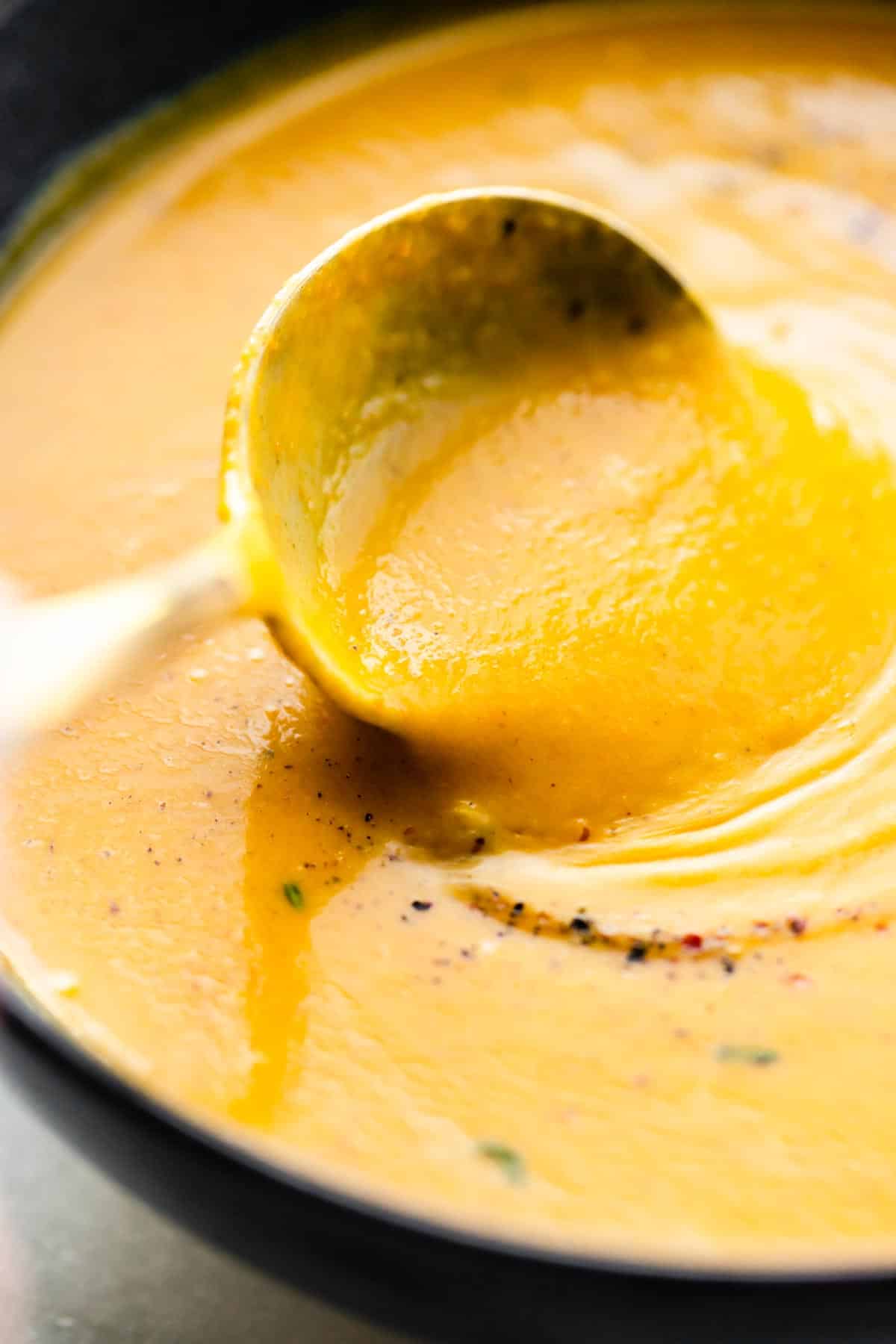 Up close photo of a spoon in a bowl of vegan butternut squash soup.