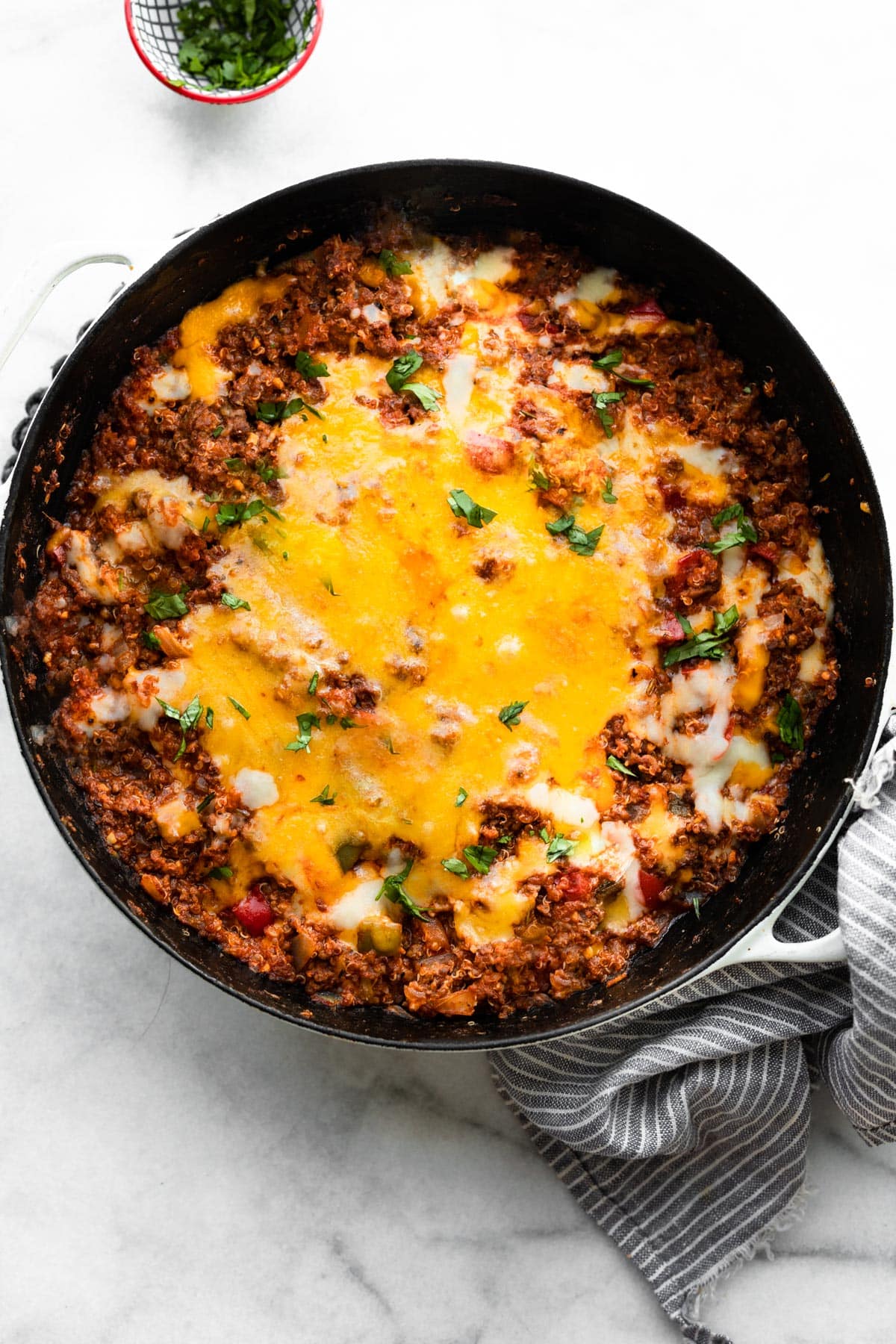 A black skillet filled with easy unstuffed bell pepper casserole on a white marble countertop.