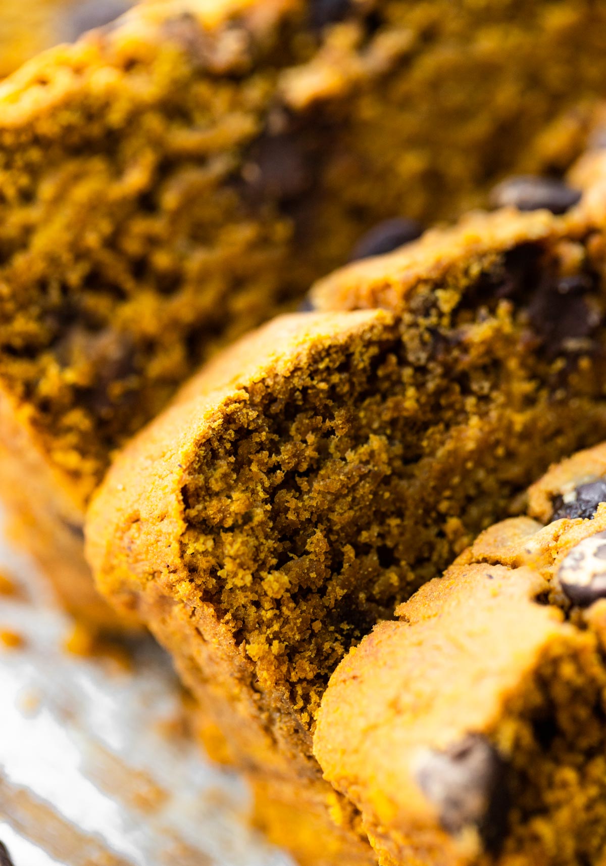 Up close photo of slices of vegan gluten free pumpkin bread topped with chocolate chips.